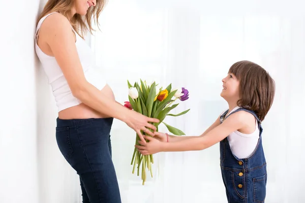 Zwangere moeder, knuffelen van haar kind, ontvangen tulpen, bloemen fo — Stockfoto