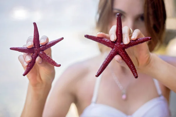 Jeune femme tenant une étoile de mer rouge à cinq doigts sur la plage — Photo