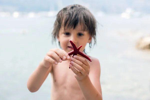 Μικρό αγόρι που κατέχουν κόκκινο σημείο πέντε αστερίες στα χέρια του στο β — Φωτογραφία Αρχείου