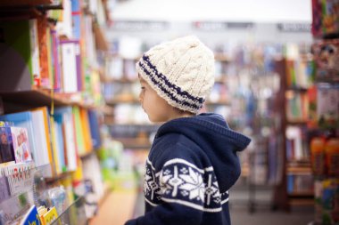 Bir kitapçıda oturan sevimli küçük çocuk