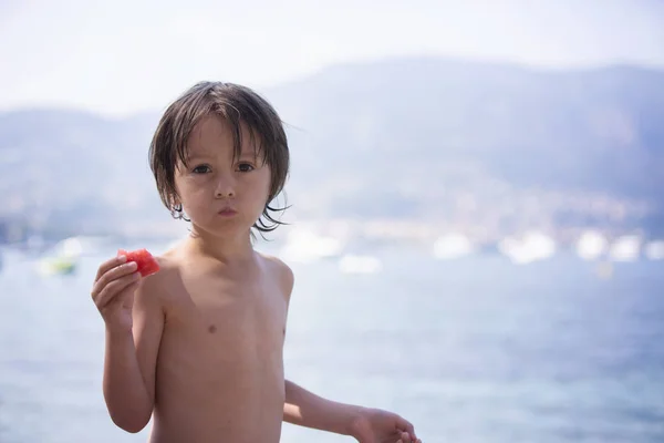 Lindo chico, comiendo un pedazo de sandía en la playa — Foto de Stock