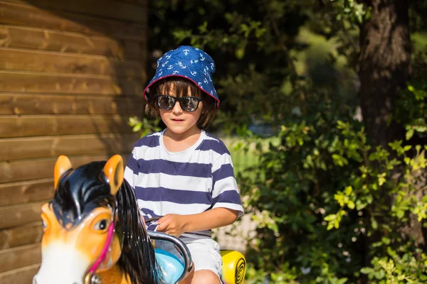 Niedliches kleines Kind, auf einem Pferd auf einem Jahrmarkt reitend — Stockfoto