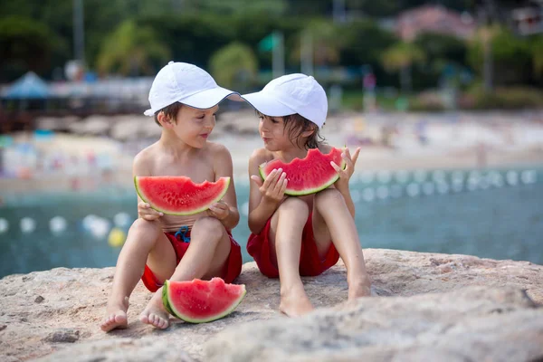 Dos niños pequeños, hermanos varones, comiendo sandía en la playa — Foto de Stock