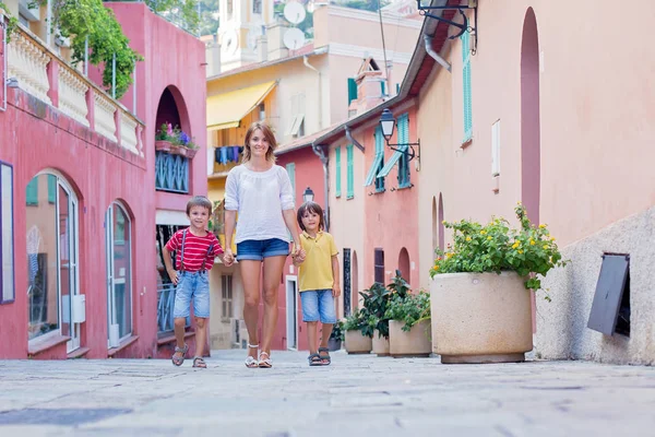 Mother and two children, walking hand in hand on a colorful stre — Stock Photo, Image