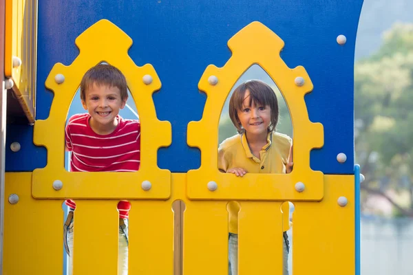 Lindos niños, hermanos, miradas a través del agujero en el patio de recreo ou —  Fotos de Stock