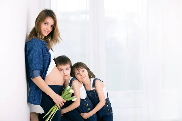 Schwangere Mutter, umarmt ihre Kinder, empfängt Tulpen, Blumen — Stockfoto