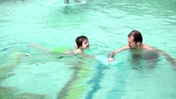 Doce criança, menino, nadando com seu pai em uma grande piscina em um feriado — Vídeo de Stock