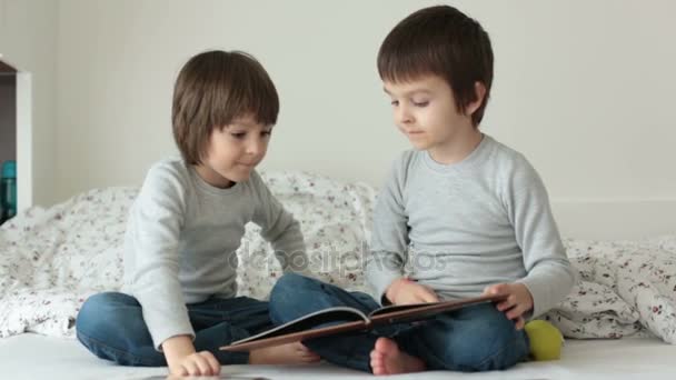 Dos lindos niños, hermanos varones, mirando el fotolibro con sus fotos, recordando — Vídeos de Stock