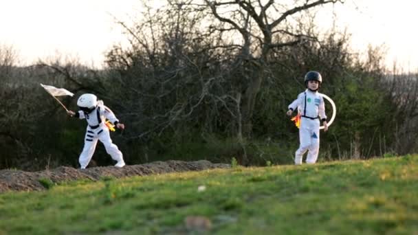 Duas crianças adoráveis, irmãos meninos, brincando no parque ao pôr-do-sol, vestidas como astronautas, imaginando que estão voando na lua — Vídeo de Stock