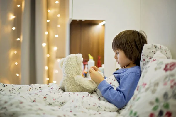 Criança doente bonito, menino, ficar na cama, brincar com ursinho de pelúcia — Fotografia de Stock