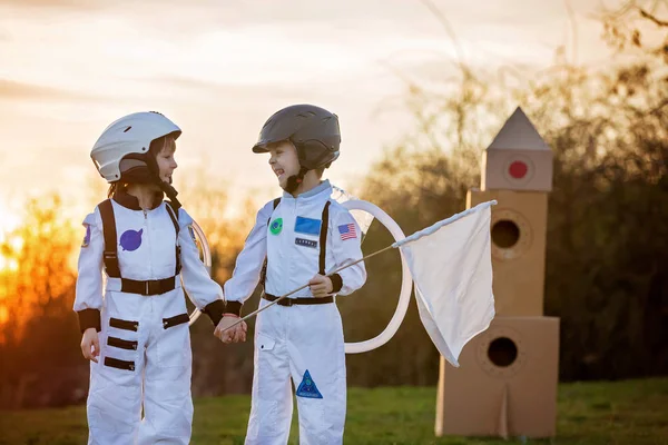 Zwei entzückende Kinder, die im Park bei Sonnenuntergang spielen, angezogen wie ein — Stockfoto