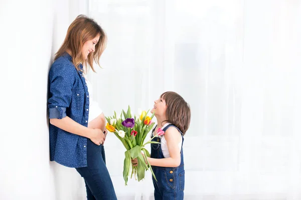 Вагітна мати, обіймає дитину, приймає тюльпани, квіти фо — стокове фото