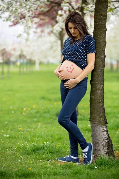 Femme enceinte dans un parc à fleurs printanières — Photo