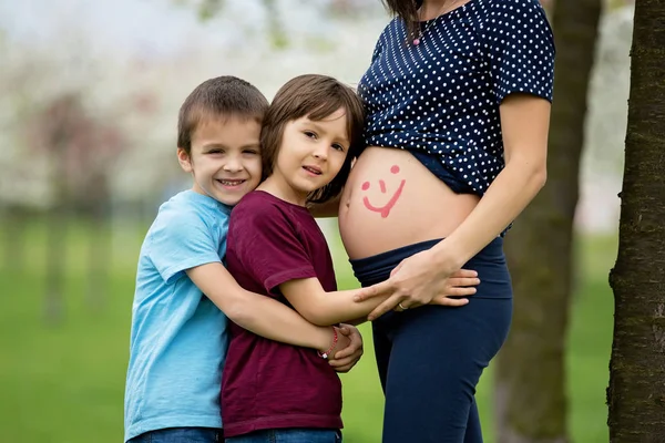 Pregnant woman and her two children in a spring blooming park — Stock Photo, Image