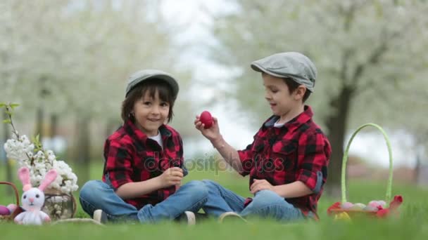 Двое детей, братья-мальчики, веселясь с яичницей в парке, красивый весенний цветущий сад — стоковое видео
