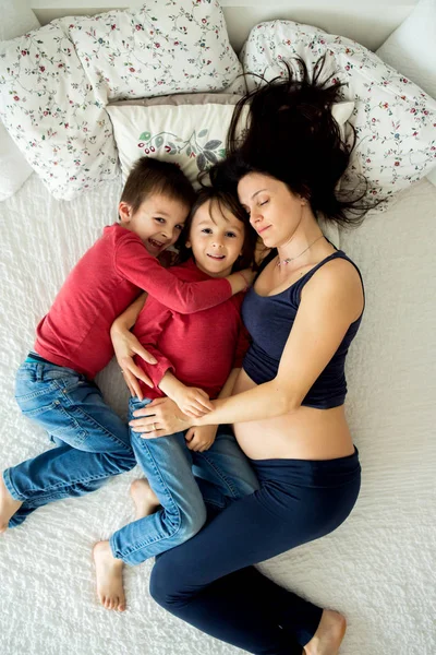 아름 다운 임신 젊은 어머니와 그녀의 아이, 소년, 침대에 lyign — 스톡 사진