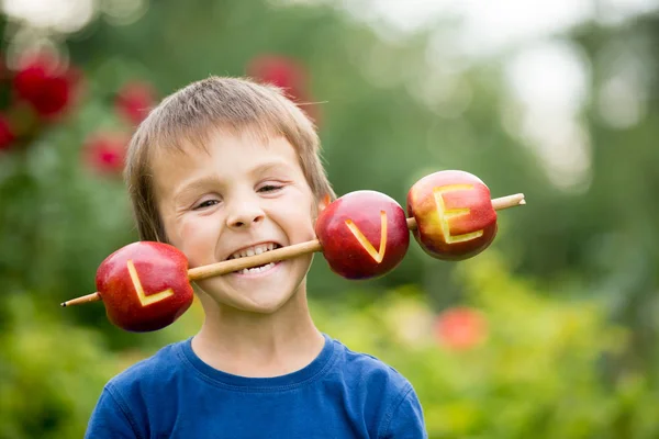 Söta lilla barn, pojke, har en skylt med kärlek, gjord på äpplen, l — Stockfoto