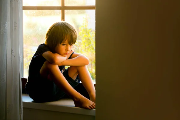 Сумна дитина, хлопчик, сидить на віконному щиті — стокове фото