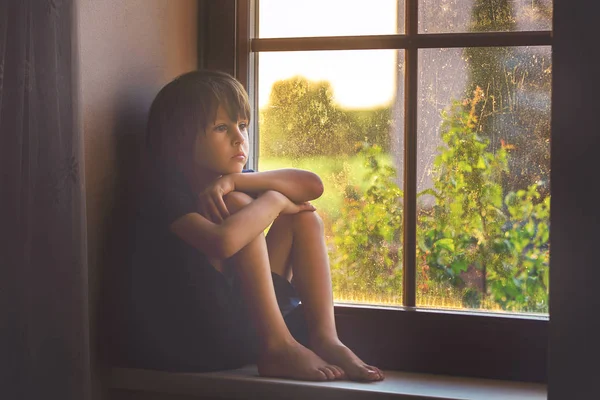 Niño triste, muchacho, sentado en un escudo de ventana —  Fotos de Stock