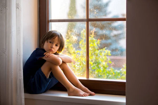 Sad child, boy, sitting on a window shield — Stock Photo, Image