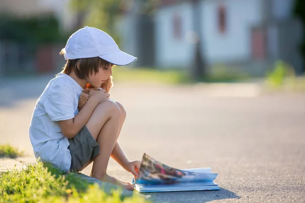 漂亮的小孩男孩，读一本书在大街上，坐下来无线 — 图库照片