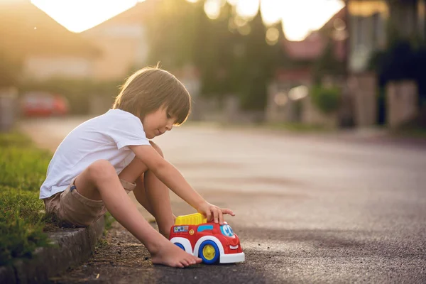 Słodkie słodkie dziecko, chłopiec, bawi się zabawkami samochodów na ulicy w vi — Zdjęcie stockowe