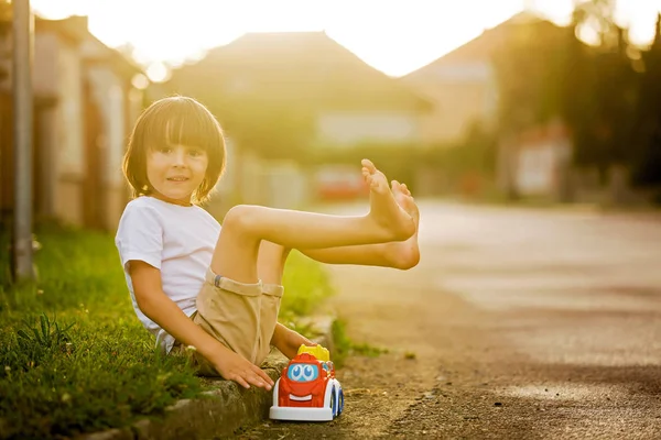 Lindo niño dulce, niño, jugando con juguetes de coche en la calle en vi — Foto de Stock