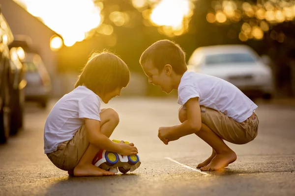 Dos niños dulces, hermanos, jugando con juguetes de coche en el s —  Fotos de Stock