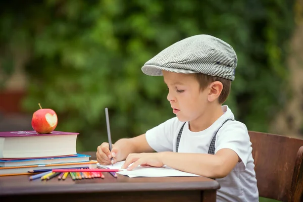 Chico, escribiendo sus deberes desde la escuela, dibujando y escribiendo en hola — Foto de Stock