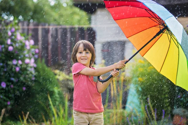 Cute adorable child, boy, playing with colorful umbrella under s — Stock Photo, Image