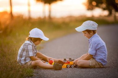 İki çocuk, erkek kardeşler, açık havada oyuncak arabalar ile eğleniyor