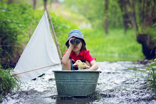 Enfant mignon, garçon, jouer avec le bateau et les canards sur une petite rive — Photo