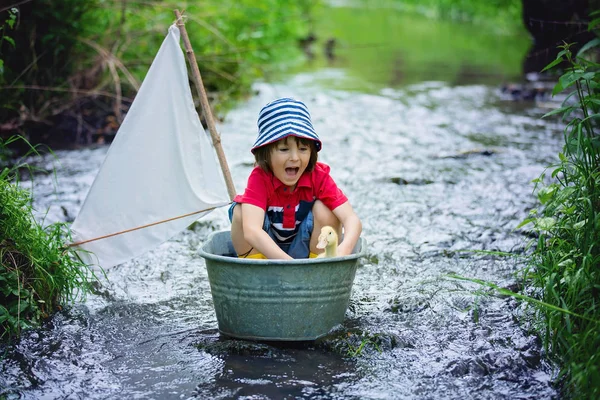 Lindo niño, niño, jugando con el barco y patos en un pequeño rive — Foto de Stock