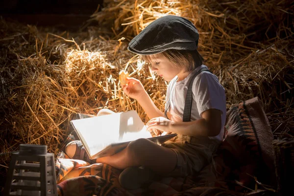Милая девочка, мальчик, читаешь книгу на чердаке дома, сидишь — стоковое фото
