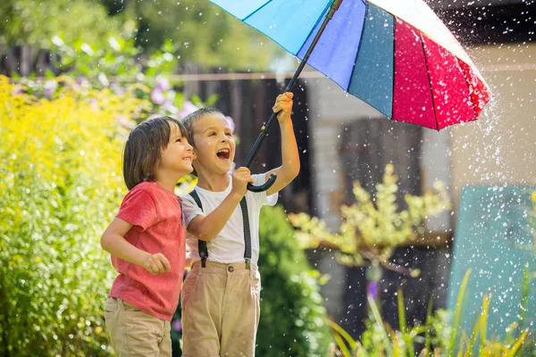 Lindo niño adorable, niño, jugando con paraguas de colores bajo s —  Fotos de Stock