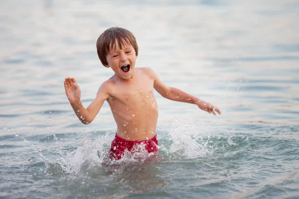 Lindo chico jugando en la playa en el agua — Foto de Stock