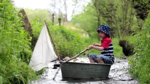 Criança gira, rapaz, brincando com barco e patos em um pequeno rio, velejando e velejando. Criança se divertindo, conceito de felicidade infantil — Vídeo de Stock