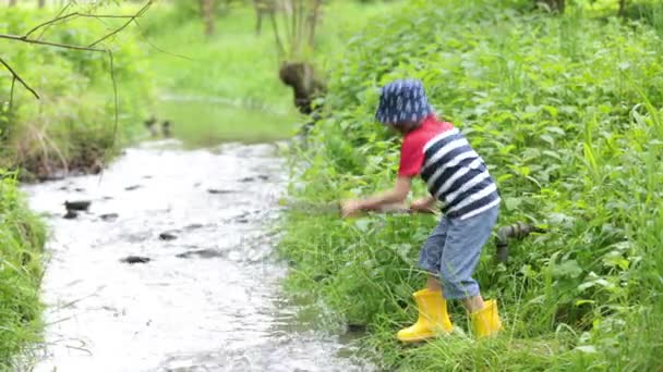 Cute little boy, playing on a little pond, splashing water springtime — Stock Video