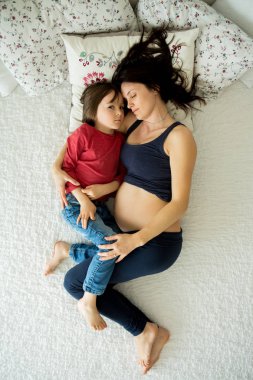 Güzel hamile genç anne ve çocuk, çocuk, yatakta yatan