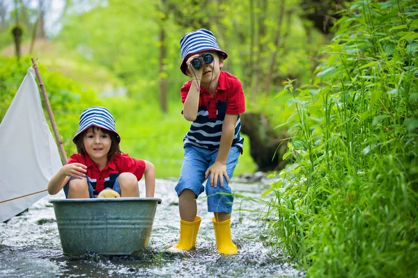Crianças bonitos, meninos, brincando com barco e patos em um pequeno riv — Fotografia de Stock