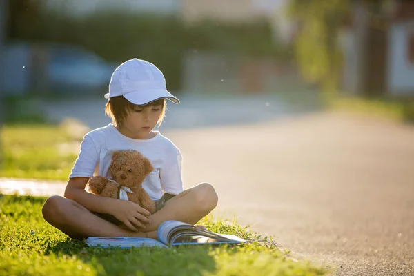 Hermoso niño, leyendo un libro en la calle, sentado wi — Foto de Stock