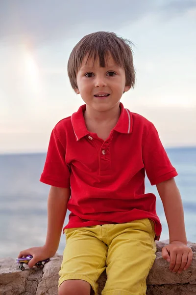 Boy, playing on the beach in the evening after rain with toys — Stock Photo, Image