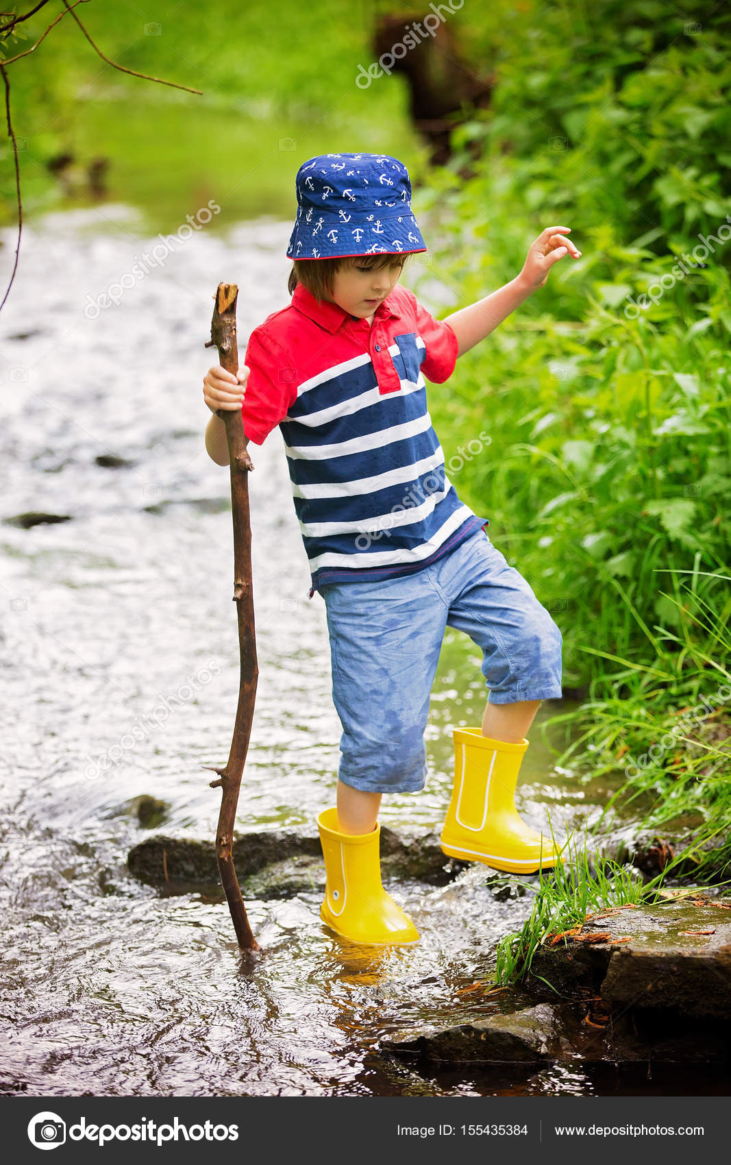 Niño pequeño con traje rojo con pala y agua puede en la calle en el