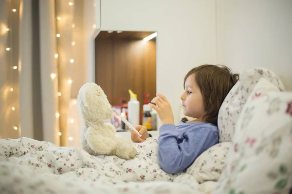 かわいい病気の子供、少年、テディベアで遊んでベッドでの滞在 — ストック写真