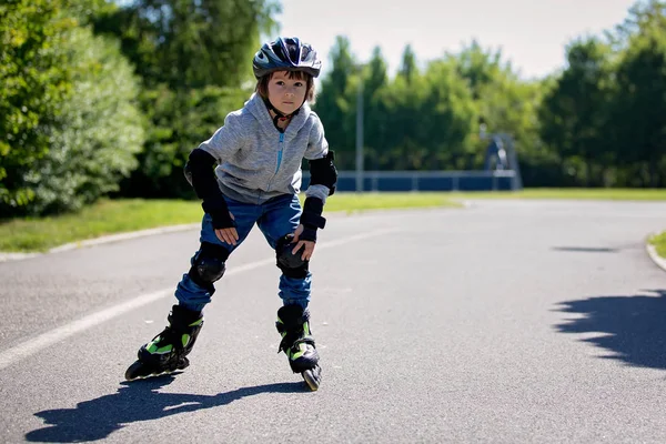 Cute little child, boy, riding on a rollerblades in the park — Stock Photo, Image