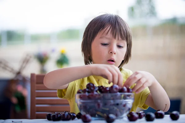 Aranyos kisfiú, étkezési cseresznye szabadban — Stock Fotó
