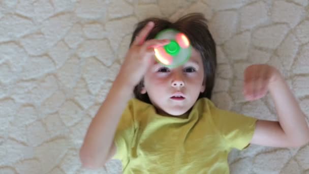 Lilla barn, pojke, leker med gröna självlysande fidget spinner leksak att lindra stress hemma — Stockvideo