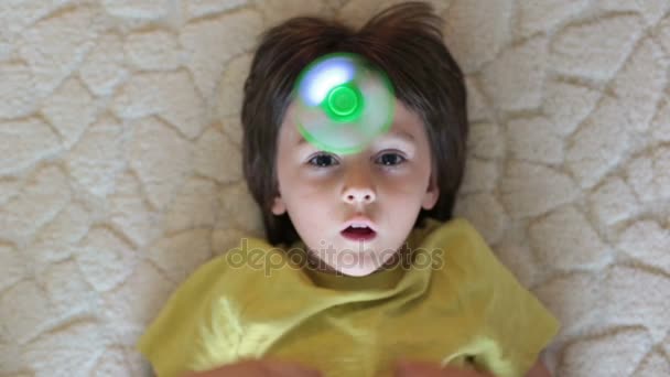 Niño pequeño, niño, jugando con el juguete giratorio luminoso verde para aliviar el estrés en casa — Vídeos de Stock