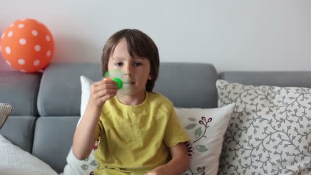 Niño pequeño, niño, jugando con el juguete giratorio luminoso verde para aliviar el estrés en casa — Vídeos de Stock