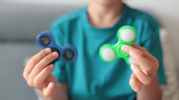 Little child, boy, playing with green and blue luminous fidget spinner toy to relieve stress at home — Stock Video